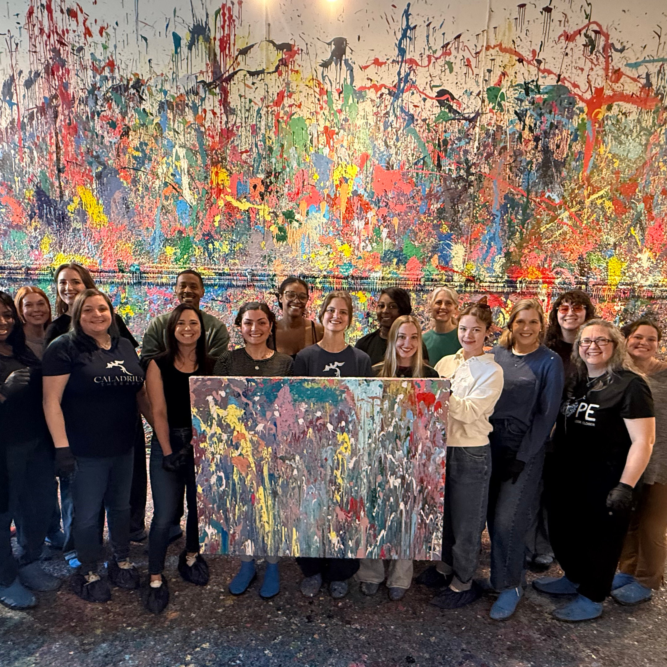The Caladrius Therapy team holding a paint canvas at a team event
